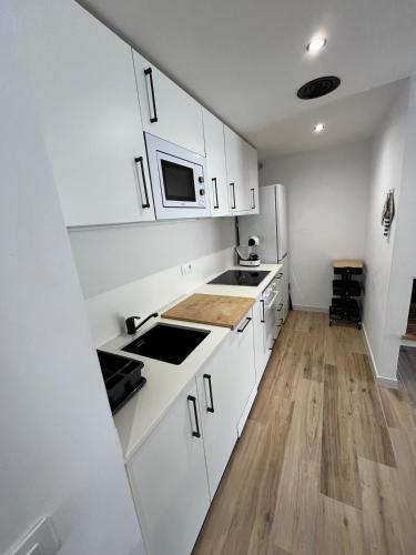 a white kitchen with a sink and a microwave at Apartament Cadaqués in Cadaqués