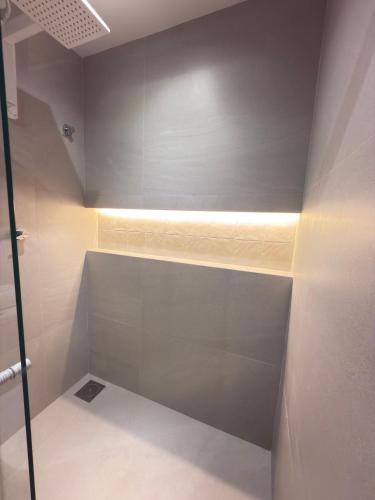 a bathroom with a walk in shower with a light at Pousada Mariá in Cabo Frio