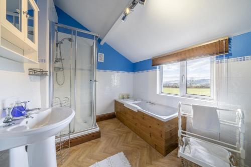 un bagno con vasca, lavandino e doccia di Drawell Cottage - Situated on a working farm a Sedbergh