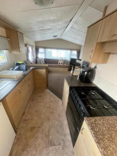 a small kitchen with a stove and a counter top at 3 Bed Caravan - Sleeps 8 - Pets - Parking - Wifi in Rhyl