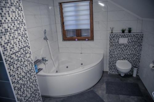 a white bathroom with a tub and a toilet at Kuća za odmor Grđan in Slatinski Drenovac
