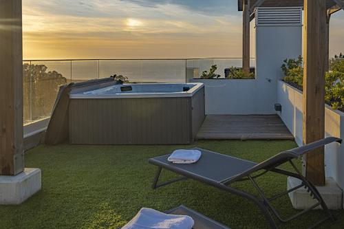 a patio with a hot tub and a chair on a balcony at Waves Nazare - by Smarthomes in Nazaré
