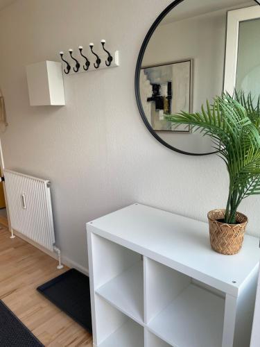 a white dressing table with a mirror and a potted plant at Herning City Apartments in Herning
