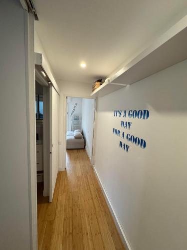 un couloir doté d'un mur blanc et d'un panneau. dans l'établissement L'AMOURETTE - Front de mer et piscine, à Saint Cyprien Plage