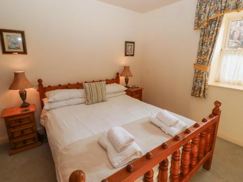 een slaapkamer met een houten bed en handdoeken bij Catkin Cottage in Wooler
