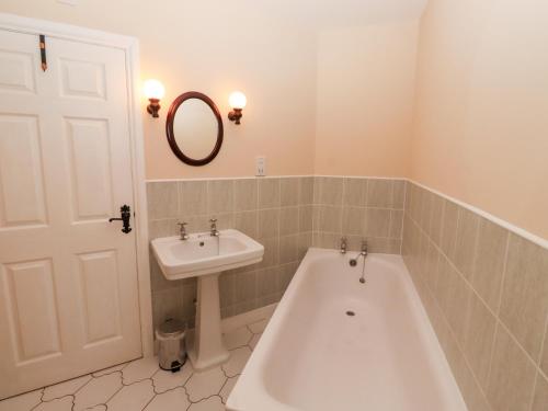 een badkamer met een ligbad en een wastafel bij Catkin Cottage in Wooler