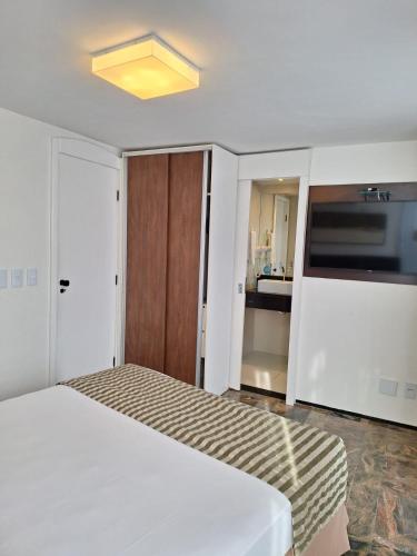 a bedroom with a white bed and a kitchen at Hotel Brasil Tropical in Fortaleza