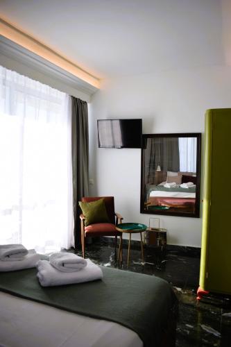 a hotel room with a bed and a chair and a mirror at Beach Side Apart II in Kavala