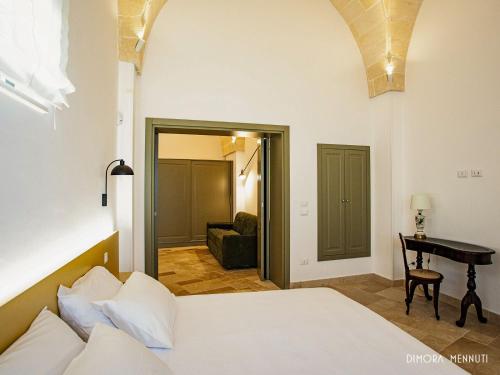 a bedroom with a bed and a desk in a room at Dimora Mennuti in Monteparano