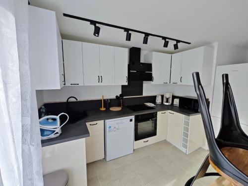 une cuisine avec des armoires blanches et un comptoir noir dans l'établissement Les Magnolias, à Brou-sur-Chantereine