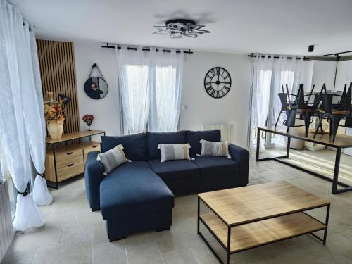 ein Wohnzimmer mit einem blauen Sofa und einem Tisch in der Unterkunft Les Magnolias in Brou-sur-Chantereine