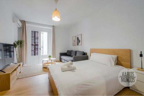 a white bedroom with a large bed and a couch at Tu balcón en Madrid para 3, Carretas 25 in Madrid