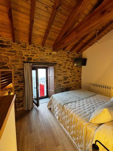 a bedroom with a bed and a stone wall at Casa Erundina in Camariñas