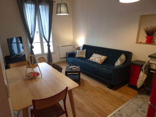 un salon avec un canapé bleu et une table dans l'établissement Paris Stade de France, à Saint-Denis