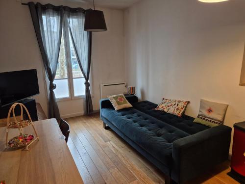 - un salon avec un canapé noir et une grande fenêtre dans l'établissement Paris Stade de France, à Saint-Denis