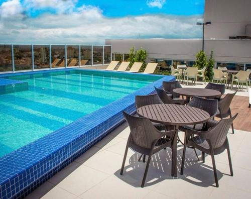 a swimming pool with tables and chairs next to a building at 0610 - Studio alto padrão in Guarulhos