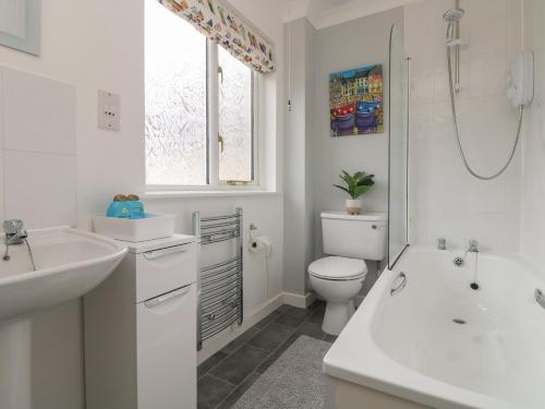 a white bathroom with a sink and a toilet at Foxglove Cottage in Falmouth