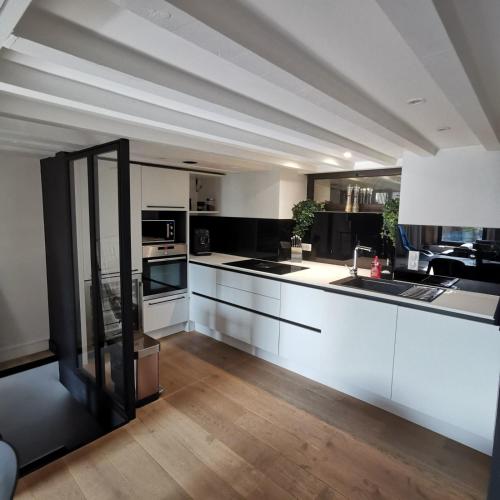 une grande cuisine avec des armoires blanches et des appareils noirs dans l'établissement Exceptional T3 with terrace in hypercentre, à Toulouse