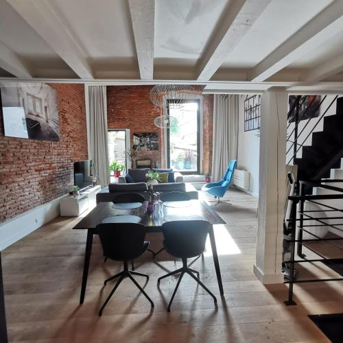 - un salon avec un mur en briques, une table et des chaises dans l'établissement Exceptional T3 with terrace in hypercentre, à Toulouse
