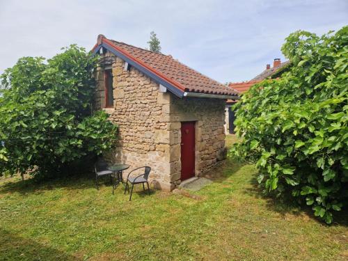 - un petit bâtiment en pierre avec une porte rouge, une table et des chaises dans l'établissement Petit gite Pèlerin, à Jabreilles-les-Bordes