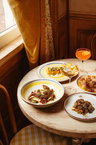 a table with plates of food and glasses of wine at Hotel Peter and Paul, an Ash Hotel in New Orleans