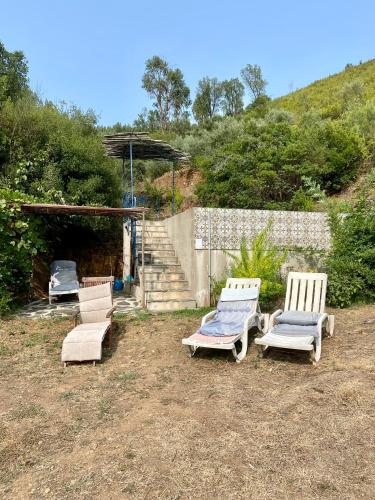 a group of three chairs sitting in a yard at Unique Tiny House with Natural Building Techniques in Figueiró dos Vinhos