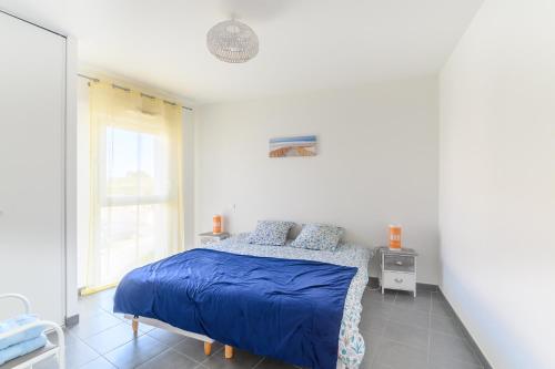 a bedroom with a bed with blue sheets and a window at Super appartement, la Guérinière à Noirmoutier in La Guérinière