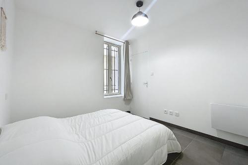 a white bedroom with a bed and a window at T2 apartment in the heart of Cuxac-d'Aude in Cuxac-dʼAude