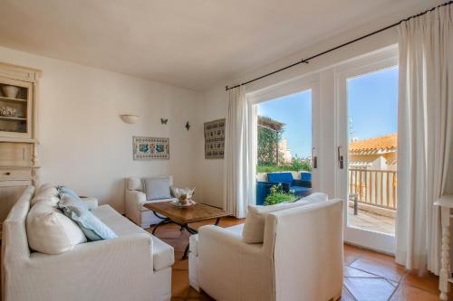 a living room with white furniture and a large window at Luxury apt in Porto Cervo square with parking in Porto Cervo