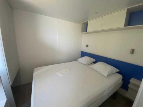 un lit blanc avec deux oreillers dans une petite pièce dans l'établissement Camping 2 étoiles - Piscine - ccb0feg, à Villeneuve-lès-Maguelone