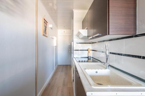 - une cuisine blanche avec un évier et une douche dans l'établissement L'Hacienda studio cosy 4 pers dans une résidence calme avec piscine belle terrasse coin nuit séparé à 300 m de la plage, au Grau-du-Roi