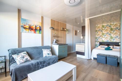 un salon avec un canapé et un lit dans l'établissement L'Hacienda studio cosy 4 pers dans une résidence calme avec piscine belle terrasse coin nuit séparé à 300 m de la plage, au Grau-du-Roi
