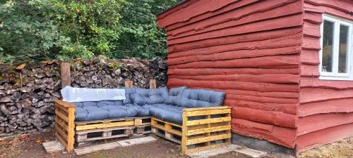 un canapé bleu assis à l'extérieur d'un bâtiment rouge dans l'établissement Cabane portager, à Jabreilles-les-Bordes