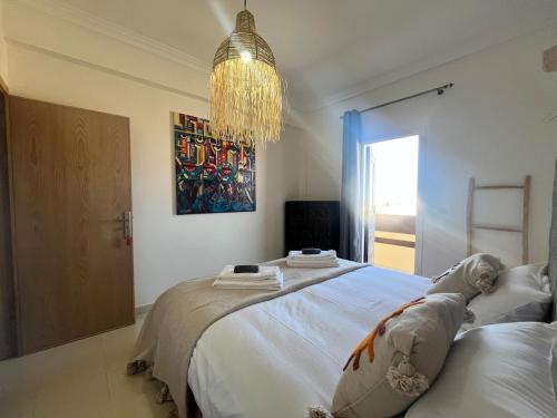 a bedroom with a large bed and a chandelier at Apartment haut standing in Ghazoua