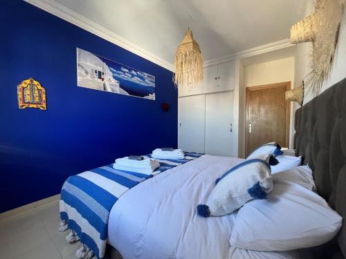 a bedroom with blue walls and a bed with pillows at Apartment haut standing in Ghazoua