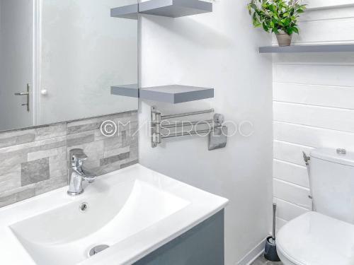 a white bathroom with a sink and a toilet at Offre à ne pas rater ! Gîtes Arc-en-ciel in Saint-François