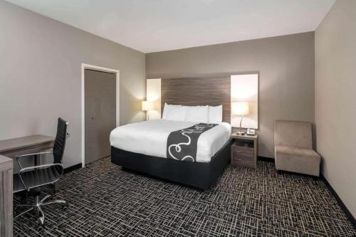 a hotel room with a bed and a desk and chair at La Quinta by Wyndham Forsyth in Forsyth