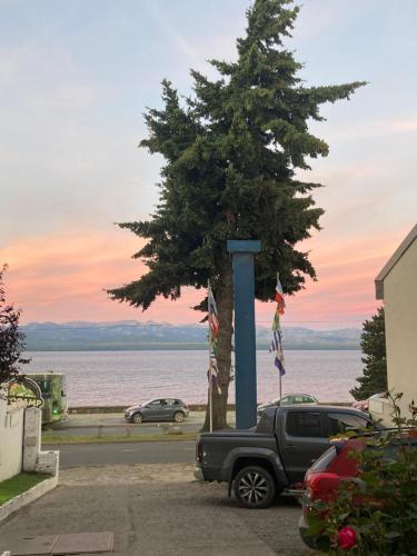 a truck parked next to a tree next to the water at Hotel Costa del Lago in San Carlos de Bariloche