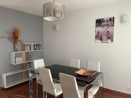 a dining room with a black table and white chairs at Edificio Acapulco in Nerja