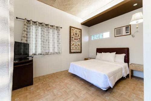 a bedroom with a white bed and a television at Tejero Highland Resort & Adventure Park in Valencia