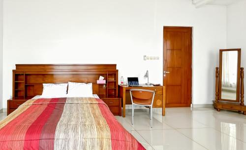 a bedroom with a bed and a desk with a computer at Kasih HomeStay Banyuwangi Mount Ijen Crater in Banyuwangi