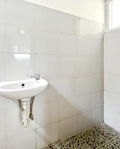 a white sink in a white tiled bathroom at Kasih HomeStay Banyuwangi Mount Ijen Crater in Banyuwangi