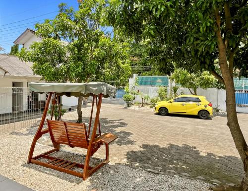 a wooden chair sitting next to a yellow car at Kasih HomeStay Banyuwangi Mount Ijen Crater in Banyuwangi