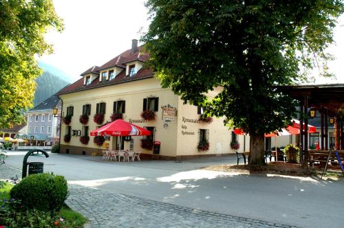 a building with a red umbrella and tables and chairs at Kronenwirt in Gurk