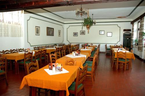 a restaurant with tables and chairs with orange table cloth at Kronenwirt in Gurk