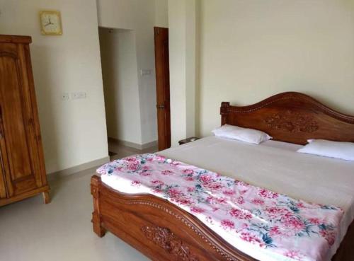 Un dormitorio con una cama de madera con una manta floral encima. en AnthillaNest, en Benaulim