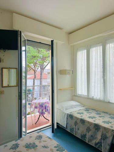 a bedroom with a bed and a balcony with a table at Hotel Erika in Rimini