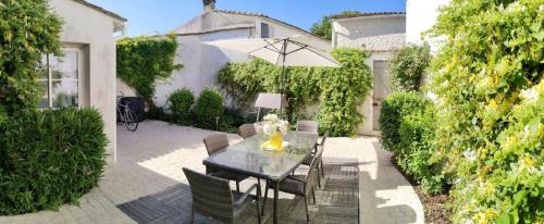 une terrasse avec une table, un parasol et des chaises dans l'établissement île de Ré , maison de ville typique rétaise au Bois-Plage, au Bois-Plage-en-Ré