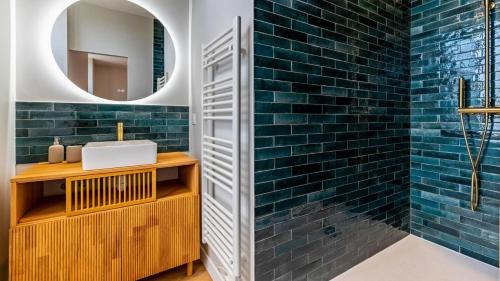 a bathroom with blue subway tiles and a sink at La maison du moussec in Les Riceys