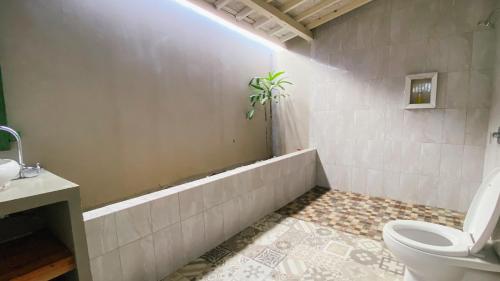 a bathroom with a toilet and a plant in the tub at Villa Olala Penida in Toyapakeh